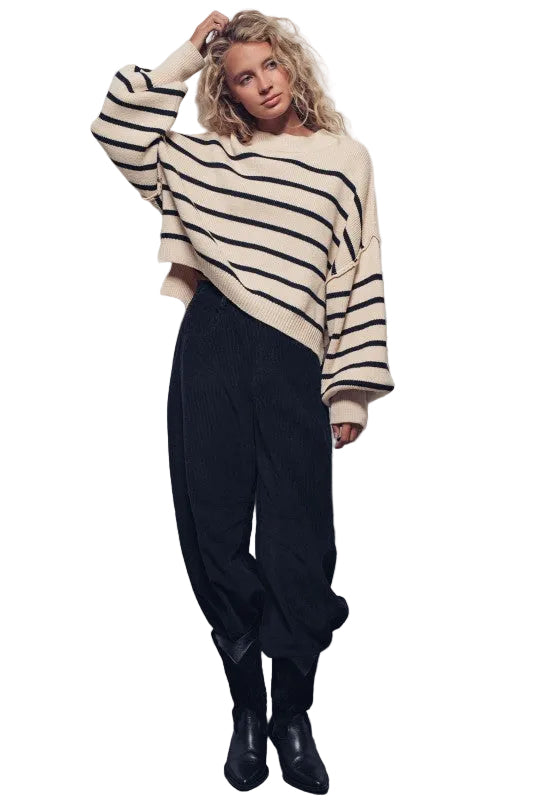 Woman wearing a striped sweater and black pants against a plain background