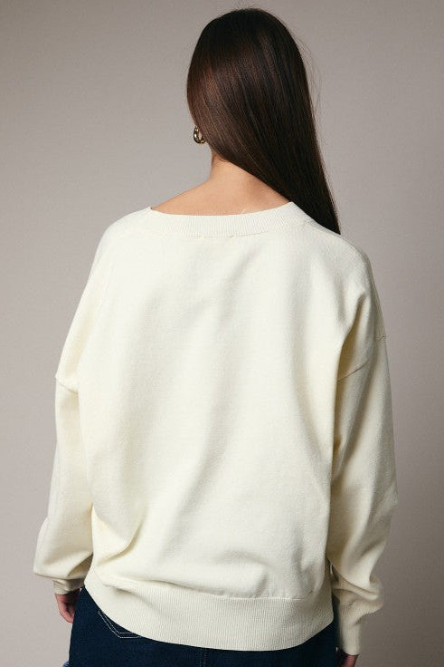 Back view of cream embroidered sweater with relaxed silhouette