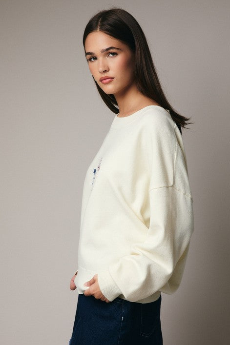 Side view of cream embroidered sweater with relaxed silhouette