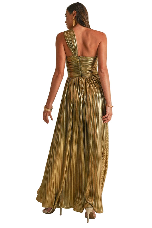 Woman wearing a gold pleated dress with an open back on a beige background