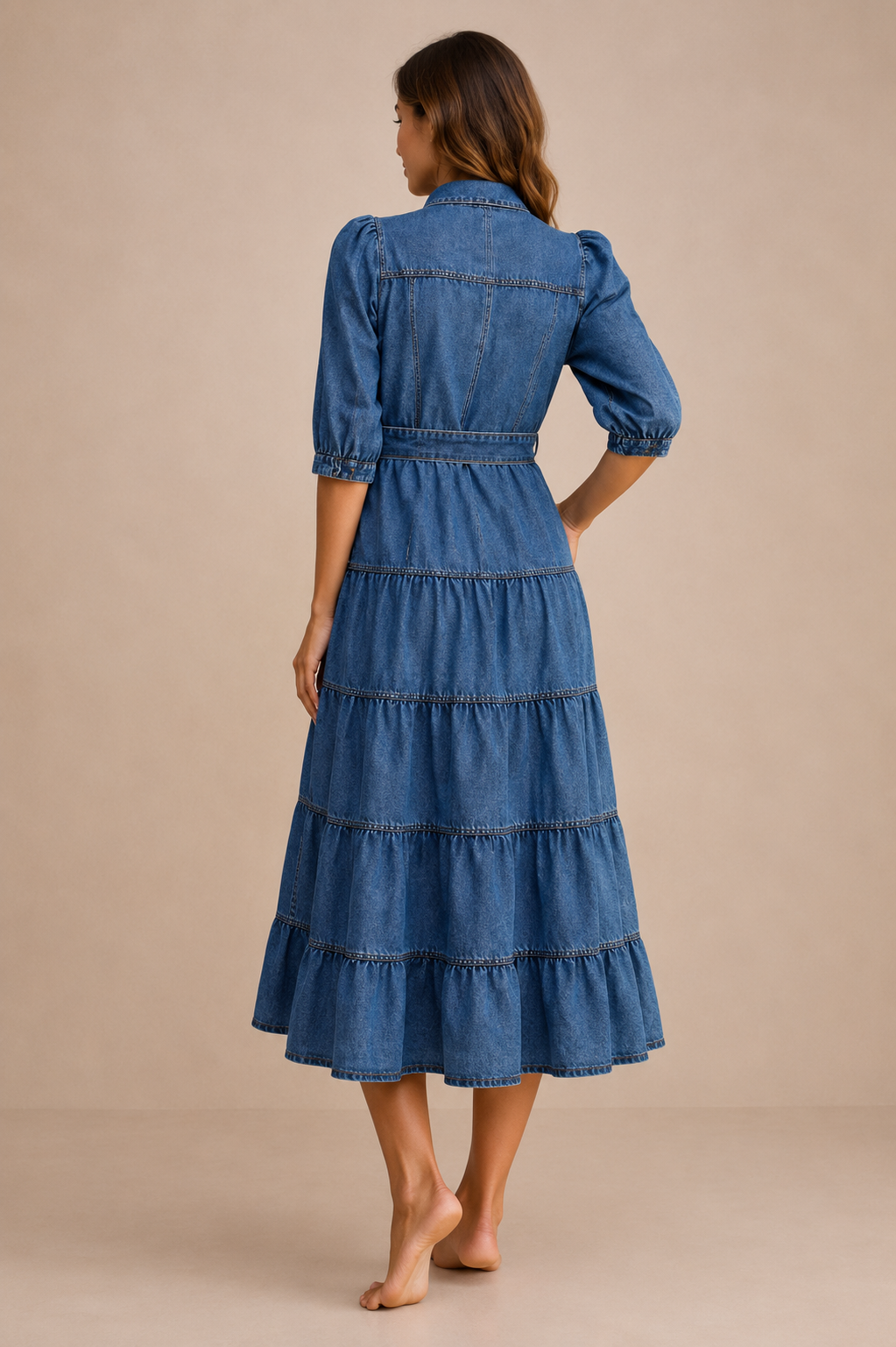 Woman over 40 showing the back view of the Denim Tiered Shirt Dress featuring lightweight denim, a button-front closure, adjustable waist tie, puff sleeves, and a relaxed midi silhouette.
