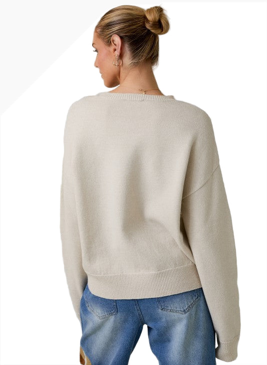 Person wearing a beige sweater and blue jeans on a plain background