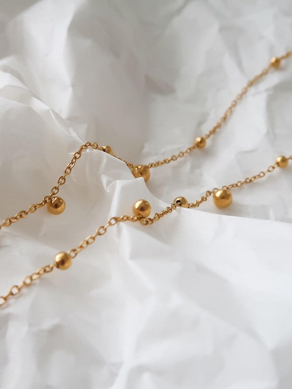 close-up detail of gold beaded Y lariat necklace with delicate chain