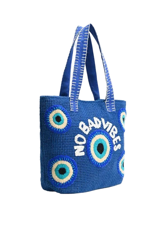 Blue woven tote bag with eye designs and 'No Bad Vibes' text on a white background